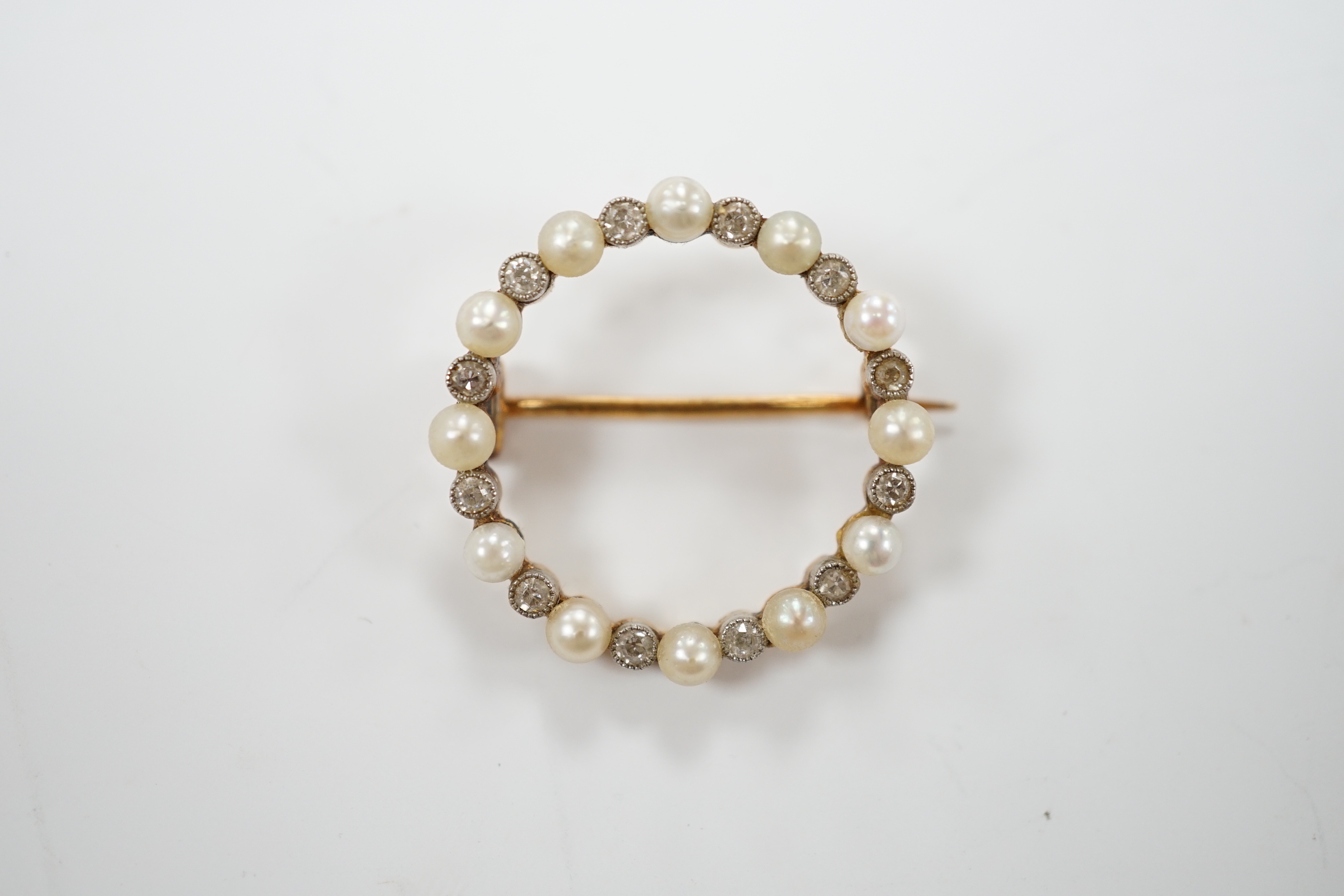 An Edwardian yellow metal, seed pearl and diamond chip set circular open work brooch, 22mm, gross weight 4 grams.